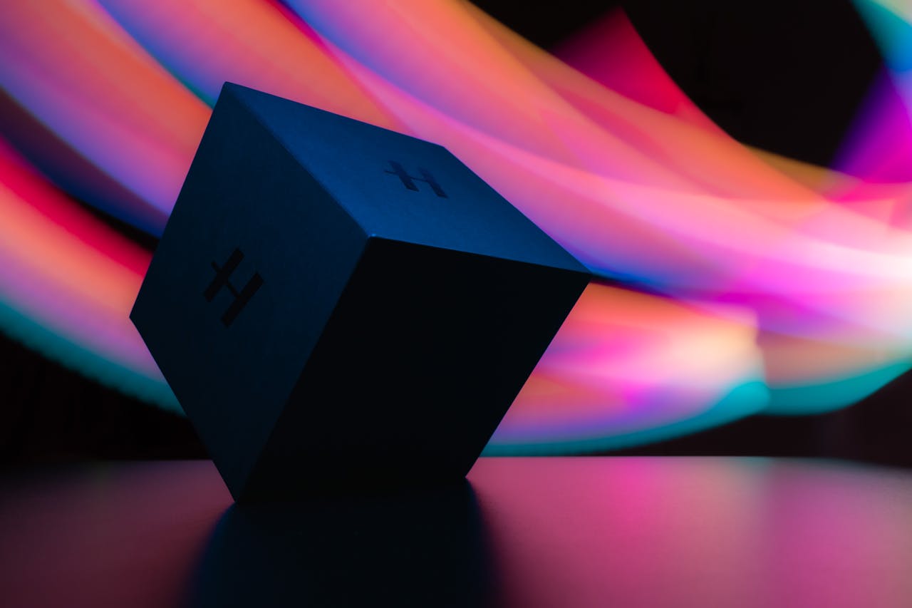 About Abstract image of a black cube with vibrant, colorful light trails in the background, creating a dynamic visual effect.