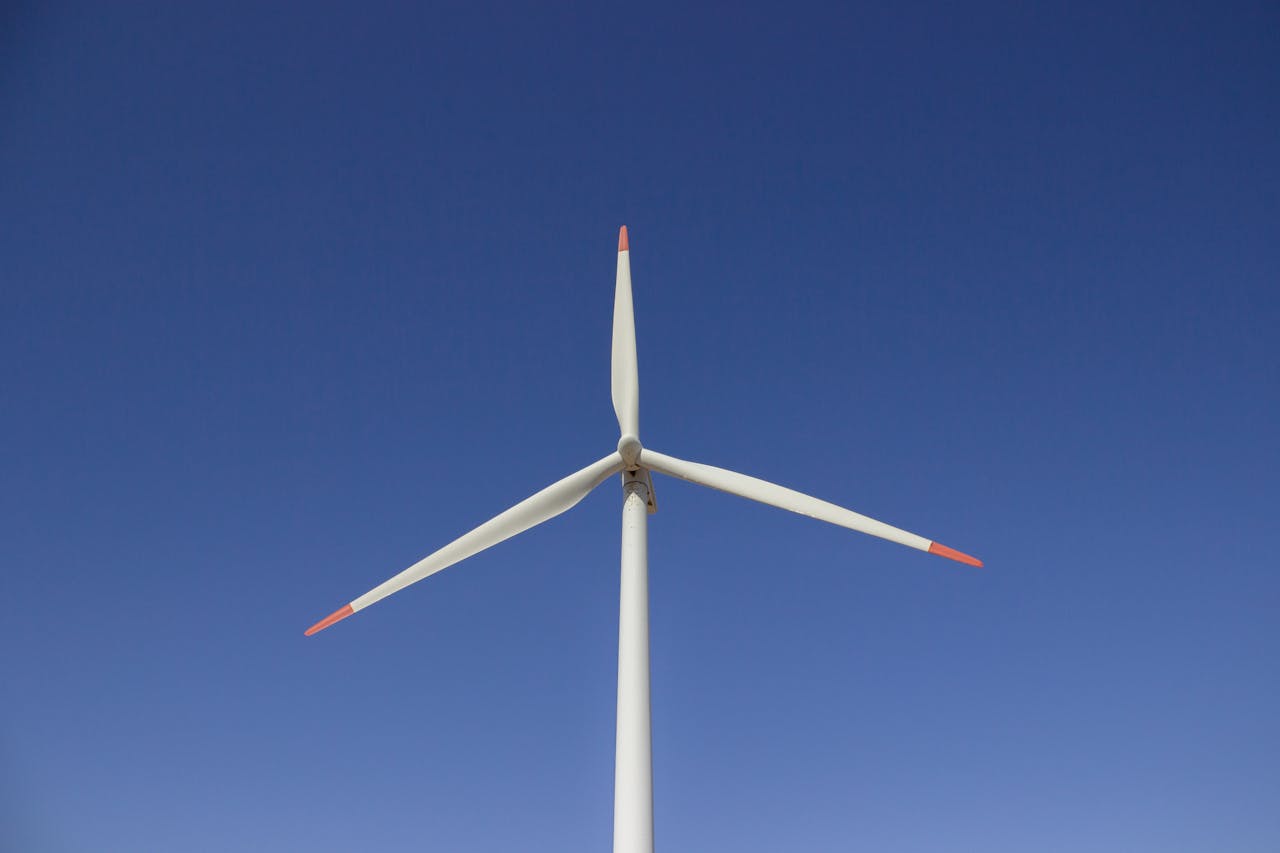 Services A wind turbine set against a clear blue sky, symbolizing clean and renewable energy.