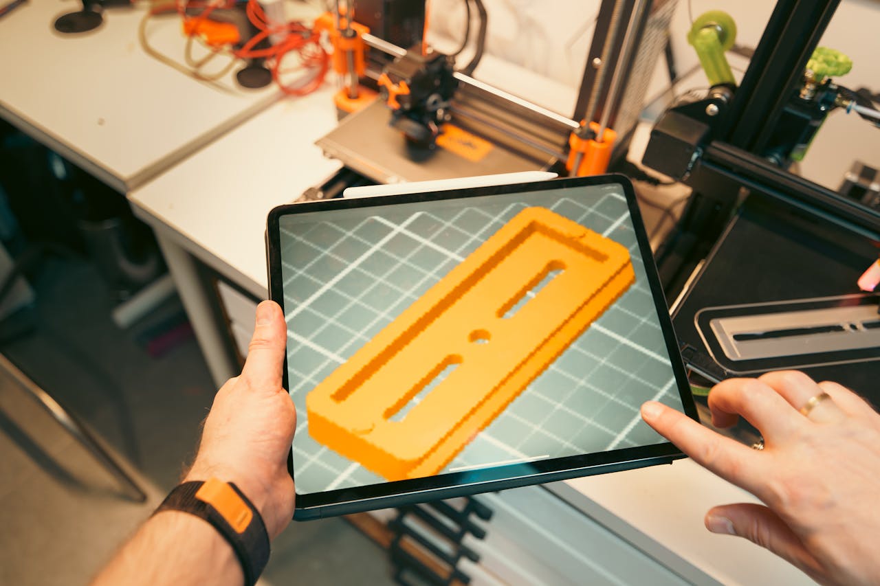 Services A person uses a tablet to view a 3D model prototype in a workshop equipped with 3D printers.